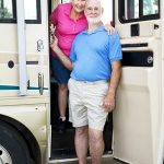 Happy Older Couple Standing In The Doorway Of Their RV
